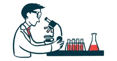 A scientist uses a microscope in a laboratory, alongside a rack of fluid-filled vials and a beaker.