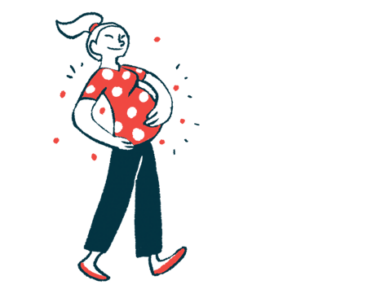 A pregnant woman cradles her belly while walking.